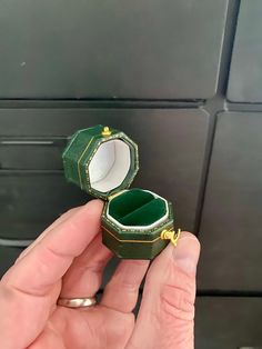 someone is holding an open ring box in their hand