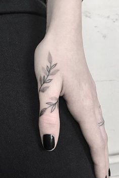 a woman's left hand with a small tattoo on the middle finger and an olive branch