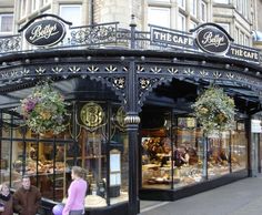 people are sitting on the bench in front of an ornately decorated building with glass doors