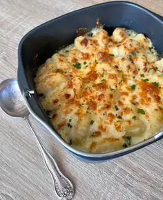 a casserole in a blue dish with a spoon next to it on a wooden table