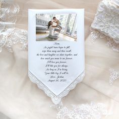 a white wedding handkerchief with an image of a bride and groom on it, next to lace doily