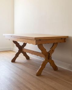 a wooden table sitting on top of a hard wood floor next to a white wall