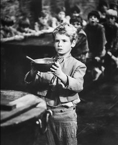 an old black and white photo of a young boy holding a frying pan