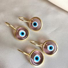 Inspired by our best-selling pendant, the breathtaking blend of colored glass and hand-painted designs in our Antique Evil Eye Earrings is bound to entice and astound. Unique in style and unmatchable in protective beauty, slip them on whenever you wish to make a strong impression, turn heads, and ignite the goddess within. 14k gold plated sterling Transparent eye .5" diameter disk Made by hand in Turkey, each piece is unique Evil Eye Hoop Earring, Cheap Blue Evil Eye Earrings, Gold Round Evil Eye Earrings, Metal Dangle Earrings With Evil Eye, Elegant Gold-plated Evil Eye Earrings, Evil Eye Earrings, Gold Baby, Eye Earrings, Evil Eye