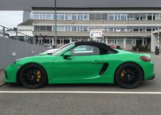 a green sports car parked in front of a building