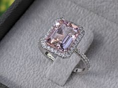 an engagement ring with a pink diamond surrounded by pave diamonds in a velvet box