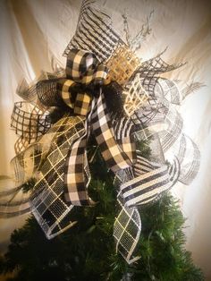 a christmas tree decorated with black and white plaid ribbon, bows and lights on it