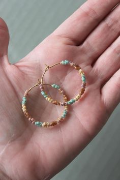 "Seed beads woven with wire onto a brass hoop making a circle of tiny, delicate flowers. This hoop measures 1.25\" in diameter.  **Please note that colors may vary slightly due to difference in monitor and phone screens**" Bohemian 14k Gold Filled Beaded Earrings, Bohemian 14k Gold-filled Jewelry With Colorful Beads, Bohemian Spring Jewelry With Colorful Beads, Spring Bohemian Jewelry With Colorful Beads, Handmade Adjustable Beaded Earrings In 14k Gold Filled, Bohemian 14k Gold Filled Earrings With Tiny Beads, Bohemian Gold Hoop Earrings For Spring, Bohemian 14k Gold-filled Beaded Earrings, Bohemian 14k Gold Filled Round Beaded Earrings