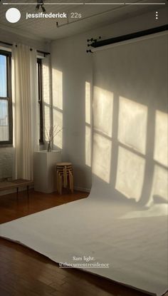 an empty room with large windows and white sheets on the floor in front of them