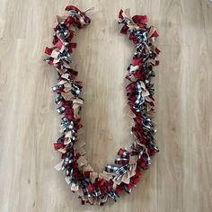 a red, white and black ribbon necklace laying on the floor