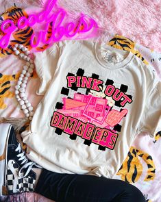 a white shirt with pink lettering on it and some other items next to it,