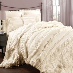 a bed with white ruffled sheets and pillows