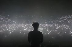 a man standing in front of a large crowd at night with lots of bright lights