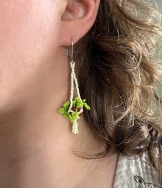 a woman wearing green and white beaded earrings