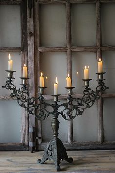 a large metal candelabra with lit candles on it in front of a window