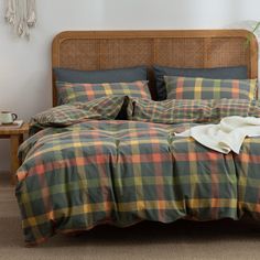 a bed with plaid sheets and pillows on top of it in a room next to a wooden headboard