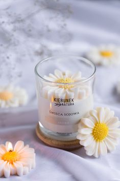 a small glass jar filled with white flowers on top of a bed of white sheets