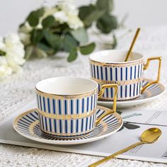 two blue and white striped cups with gold trimmings on them, sitting next to each other