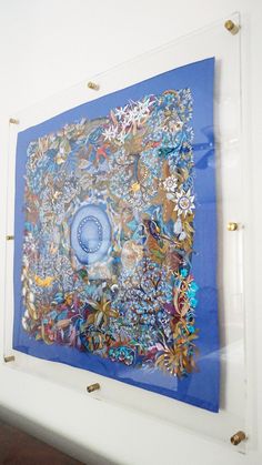 a blue painting hanging on the wall in a white walled room with gold studding