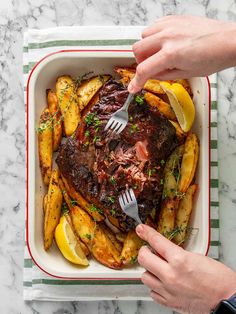 a person is holding a fork and knife over a pot roast with french fries on the side