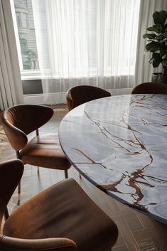 an oval marble dining table with chairs around it