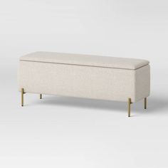 an upholstered bench with wooden legs and a white fabric cover on the back