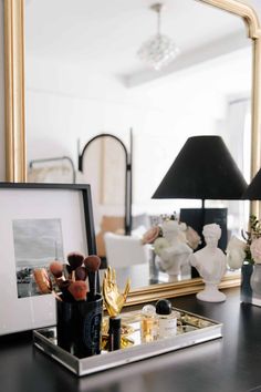 a black desk topped with a mirror and lots of makeup