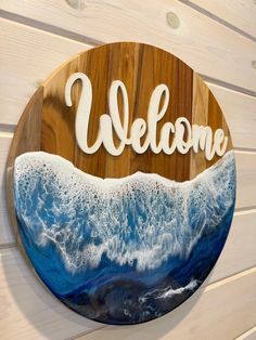 a wooden sign that says welcome on the side of a wall with waves in it