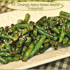 a white plate topped with green beans covered in sesame seeds