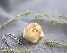 This white rose necklace is part of my white flower jewelry collection. Imagine this unique creation in your hands: A real rose flower necklace as the best bridesmaid gift or as a personalized gift. This dainty rose necklace is possibly the most original bridesmaid flower necklace. Its elegance and beauty make it perfect for formal occasions (over dark colors) or informal (over pastel or light colors). This white rose necklace comes with a hypoallergenic stainless steel collar. The resin provide Rose Flower Pendant Necklace For Wedding, Rose Flower Jewelry For Bridesmaid Gift, Elegant White Pressed Flower Necklace, Rose Gold Roses Necklaces For Wedding, Delicate Flower Necklace For Wedding With Round Pendant, Delicate Flower Necklace With Round Pendant For Wedding, Delicate Wedding Flower Necklace With Round Pendant, White Rose Design Necklace As Gift, White Rose Design Necklace For Gift