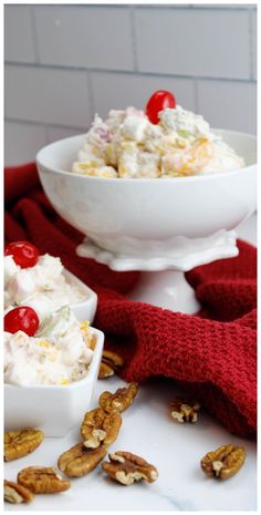 two bowls filled with fruit salad on top of a white counter next to pecans