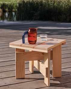 a wooden table with a pitcher on it and a cup sitting on top of it