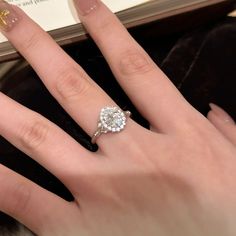 a close up of a person's hand with a diamond ring on their finger