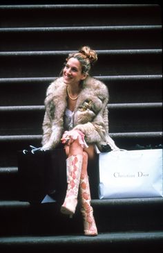 a woman sitting on the steps with her legs crossed and bags in front of her