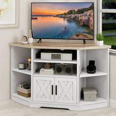 a flat screen tv sitting on top of a white entertainment center next to a window