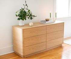 a wooden dresser sitting on top of a hard wood floor next to a white wall