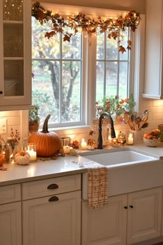 a kitchen filled with lots of candles next to a sink and window covered in fall leaves