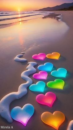 the sun is setting on the beach with hearts in the sand