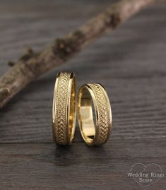 two gold wedding rings sitting on top of a wooden table