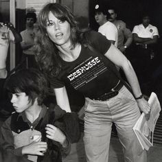 black and white photograph of woman with child on skateboard in front of other people