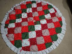 a red and green patchwork quilted table cloth on top of a white doily