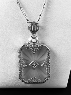 "A lovely and very feminine 1930's vintage necklace featuring a frosted pressed glass plaque-known as Camphor Glass. Delicate lacy platinum filigree sets the background for a single tiny twinkling diamond in the center.The pendant is topped with a matching filigree crown-like bail. Inside the bail is stamped \"Plat\" The pendant comes with the original 14k antique chain, although I would not trust this chain , because of it's age and condition to be able to withstand any type of wear. I can prov Vintage Jewelry With Rectangular Pendant For Formal Occasions, Vintage Rectangular Pendant Jewelry For Formal Occasions, Vintage Diamond Cut Pendant Jewelry, Vintage White Gold Diamond-cut Necklace, Vintage Engraved White Gold Necklace, Elegant Formal Necklace With Vintage Charm, Vintage Engraved Necklaces For Formal Occasions, Elegant Vintage Charm Necklace For Formal Occasions, Vintage Diamond Cut Silver Necklace