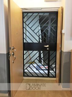 an open door leading into a room with wooden flooring and black iron bars on the doors