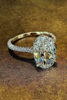 an oval cut diamond ring sitting on top of a table