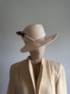 "This striking vintage hat features a face-framing brim; a soft, cream felt body; and an elegant, arching pheasant feather and wool \"bow.\"  Era: 1970s  Label: Peachfelt | 100% wool | Geo W Bollman and Co USA Pictured on a mannequin with a 21 inch head circumference About Geo W Bollman hat company from their website:  * Bollman Hat Company is the oldest hat maker in America, and among the world's oldest because of a stewardship culture and a continuous focus on our innovation, unsurpassed quali Formal Beige Fedora With Short Brim, Classic Fitted Beige Hats, Classic Beige Fedora Felt Hat, Classic Cream Hats With Short Brim, Cream Fedora Hat For Formal Occasions, Classic Cream Fedora For Formal Occasions, Chic Fedora With Curved Brim For Formal Occasions, Elegant Fedora Hat For Fall, Fitted Beige Fedora With Flat Brim