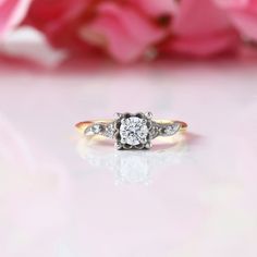 a close up of a diamond ring with pink flowers in the background