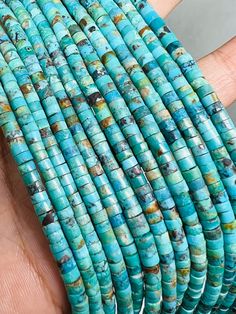 a hand holding several pieces of turquoise colored beads