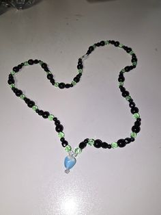 A beautiful one of a kind black and green hand beaded glass necklace. Pair it with the perfect outfit or gift it to a loved one! Black Glass Round Bead Jewelry, Black Glass Round Beads Jewelry, Black Beaded Glass Necklaces, Black Glass Beaded Necklaces With Round Beads, Black Beaded Glass Necklace, Black Glass Beaded Necklace With Round Beads, Black Czech Glass Jewelry With Round Beads, Handmade Black Czech Glass Necklaces, Handmade Glass Beads In Black