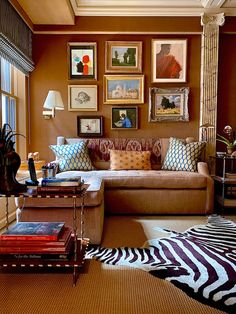 a living room filled with lots of furniture and pictures on the wall above it's windows