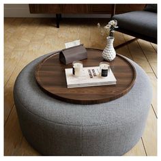 a round coffee table with magazines on it and a vase filled with flowers in the middle